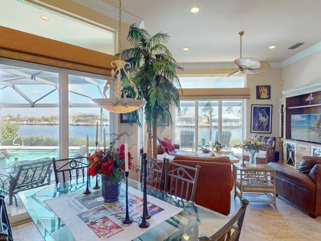 Tiled dining area with ornamental molding, a water view, and ceiling fan
