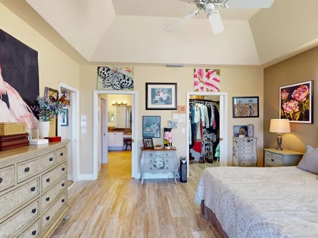 Bedroom featuring a tray ceiling, light wood-type flooring, a closet, and ceiling fan