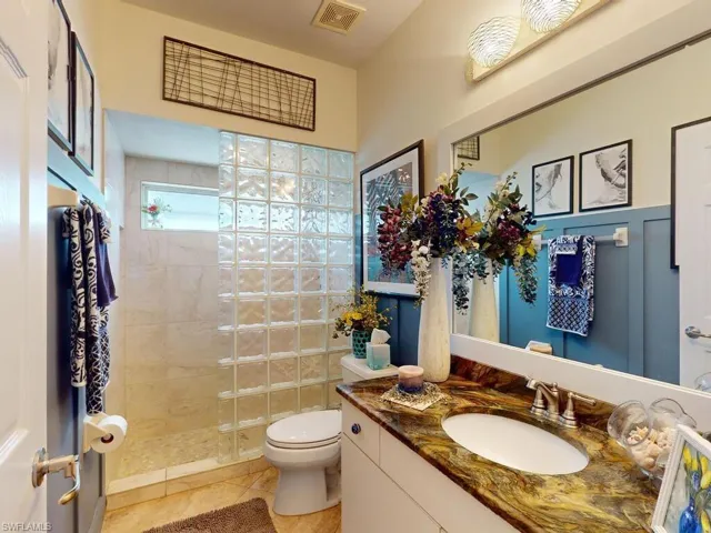 Bathroom featuring vanity, a tile shower, toilet, and tile patterned floors