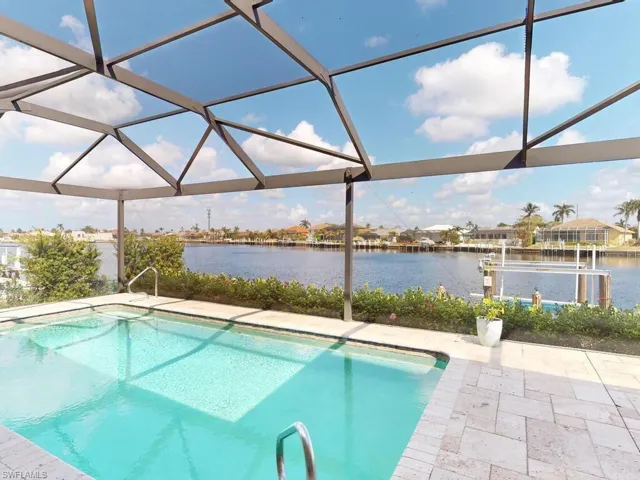 View of pool with a water view, a patio, and glass enclosure