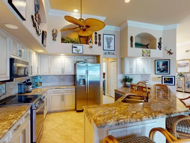 Kitchen with a kitchen breakfast bar, an island with sink, ornamental molding, sink, and appliances with stainless steel finishes