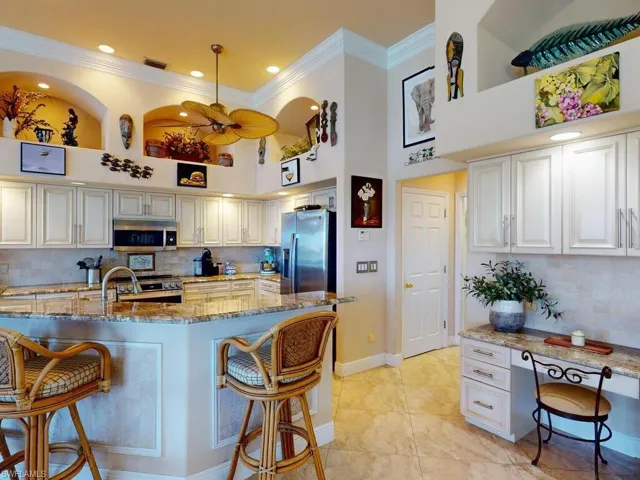 Kitchen featuring white cabinets, a breakfast bar, dark stone countertops, a high ceiling, and stainless steel appliances