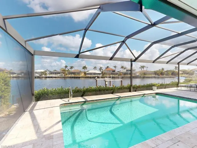 View of swimming pool featuring a patio, a water view, and glass enclosure