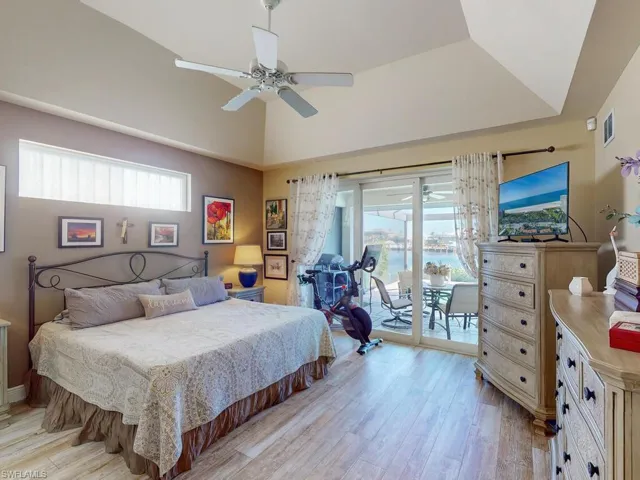 Bedroom featuring vaulted ceiling, light hardwood / wood-style flooring, access to exterior, and ceiling fan