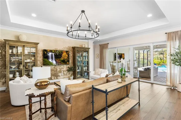 Living room featuring a tray ceiling, hardwood / wood-style flooring, and suspended lighting