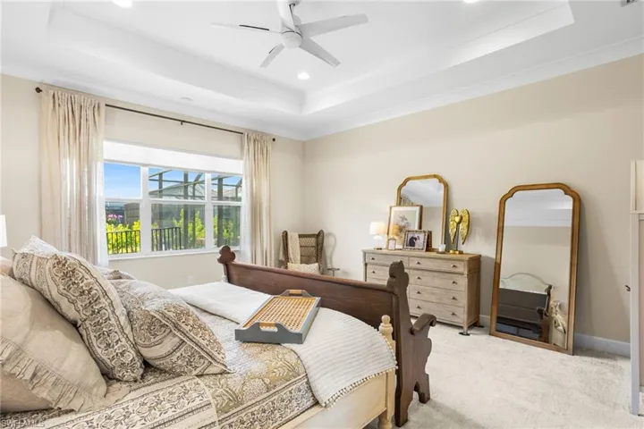 Bedroom featuring carpet flooring, ceiling fan, ornamental molding, recessed lighting, and a tray ceiling