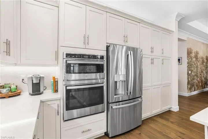 Kitchen featuring stainless steel appliances, dark wood-style floors, white cabinets, and crown molding