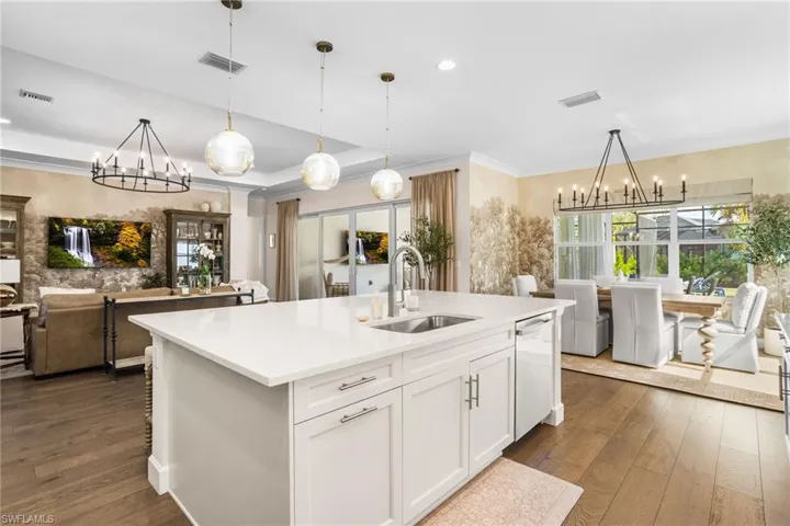 Kitchen with suspended lighting, white cabinets, open floor plan, dark wood-style flooring, and a raised ceiling