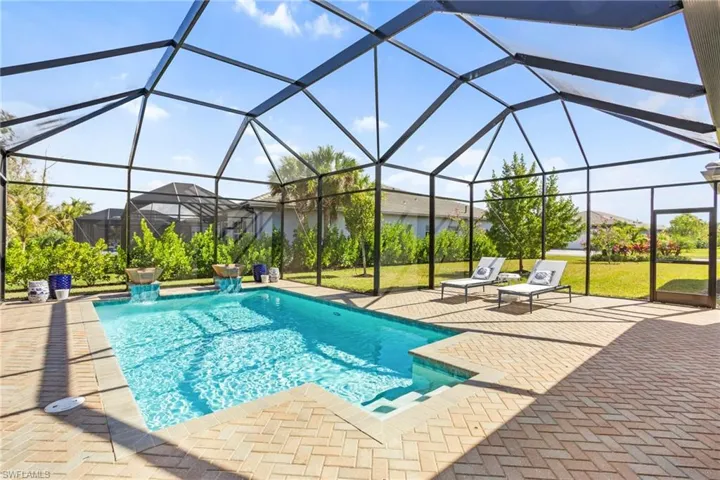 Swimming pool featuring glass enclosure, a patio, a sunroom, and a yard