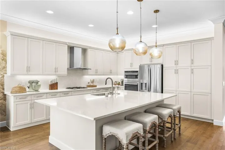 Kitchen with dark wood-style floors, stainless steel appliances, a kitchen breakfast bar, and white cabinets