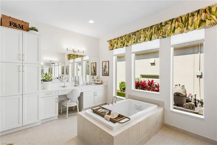 Bathroom with vanity, a bath, light tile patterned floors, and recessed lighting