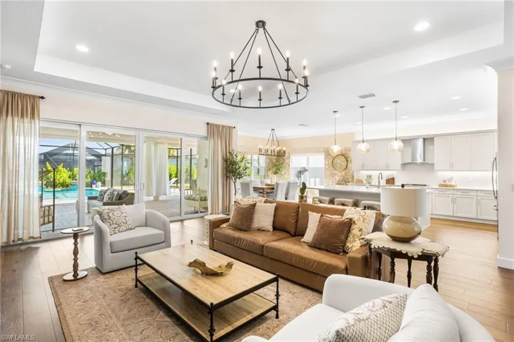 Living room featuring light wood finished floors, a chandelier, and a raised ceiling