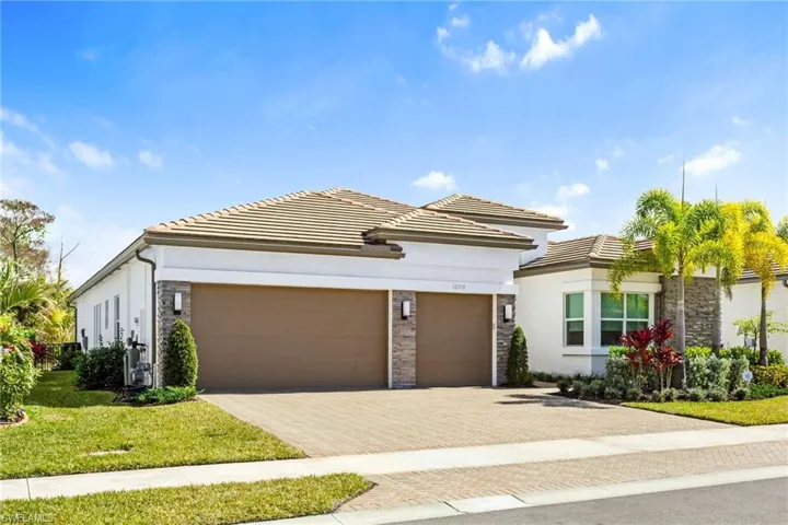 View of front of house featuring stone siding, decorative driveway, stucco siding, and a garage