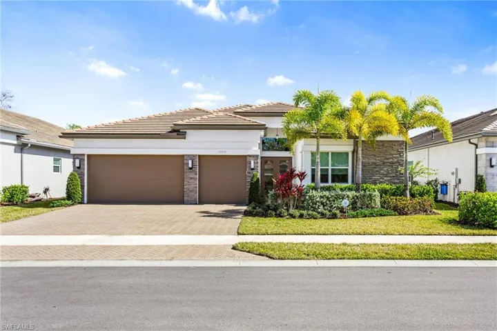 View of front of home with decorative driveway, stone siding, an attached garage, and stucco siding