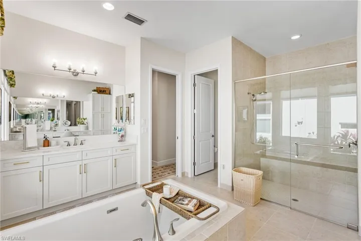 Full bath with vanity, a stall shower, a garden tub, light tile patterned flooring, and recessed lighting