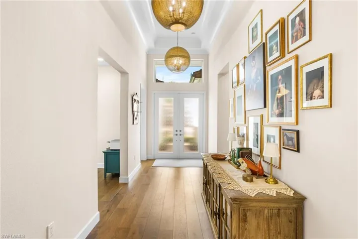 Foyer entrance with hardwood / wood-style flooring, french doors, a raised ceiling, and a chandelier