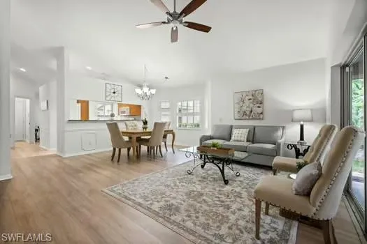 Living area featuring light wood-type flooring, ceiling fan, and a chandelier