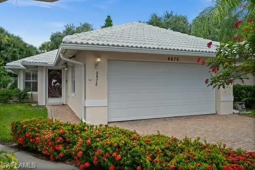 View of front facade featuring stucco siding, driveway, an attached garage, and a tiled roof