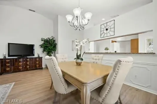 Dining area with light wood finished floors, a chandelier, and recessed lighting