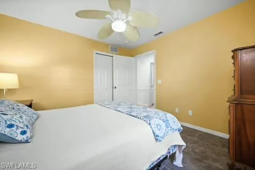 Bedroom with ceiling fan and dark tile patterned flooring