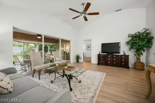 Living area with light wood-type flooring, a ceiling fan, and high vaulted ceiling