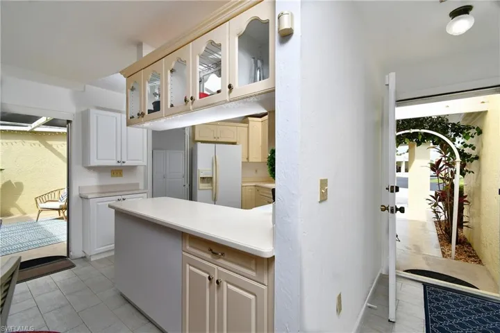 Kitchen with light tile floors and white refrigerator with ice dispenser