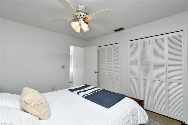 Tiled bedroom with two closets and ceiling fan