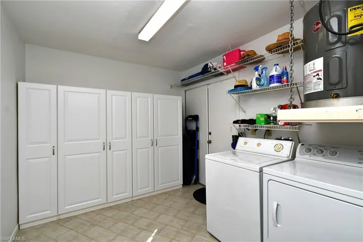 Laundry room featuring washer and dryer, hookup for a washing machine, light tile floors, and electric water heater