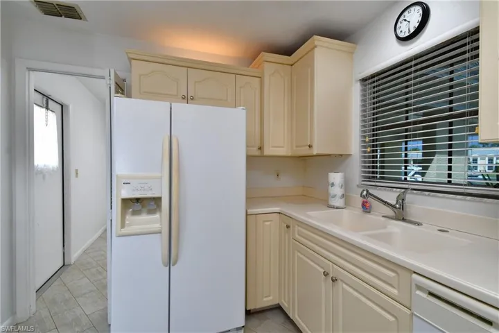 Kitchen with sink, light tile flooring, and white appliances
