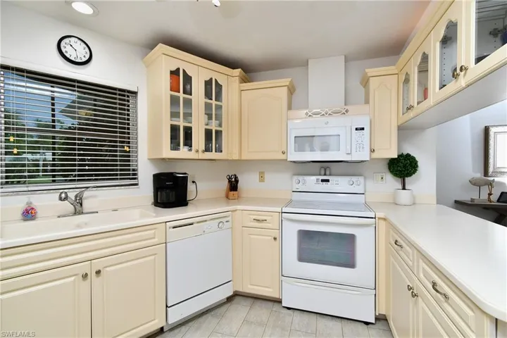 Kitchen with white appliances, sink, and cream cabinets