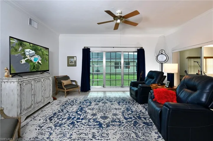 Tiled living room with ceiling fan and ornamental molding