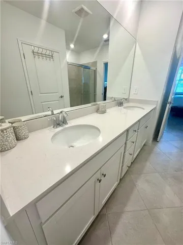 Bathroom with double vanity, a stall shower, and light tile patterned floors