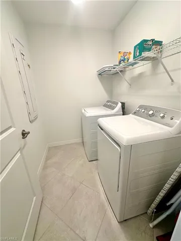 Laundry room featuring light tile patterned floors, washer and dryer, and electric panel