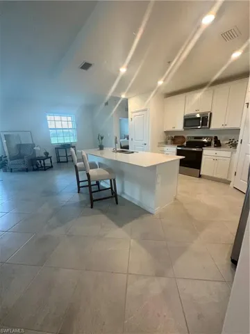 Kitchen featuring stove, white cabinets, a breakfast bar area, and light tile patterned floors