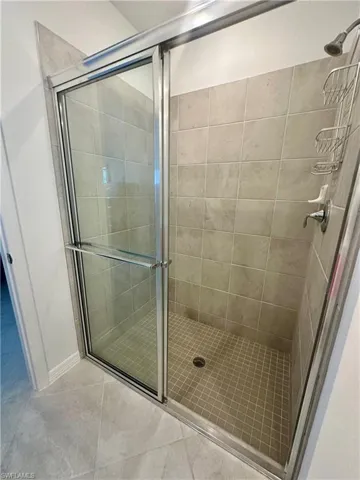 Bathroom with a shower stall and light tile patterned floors
