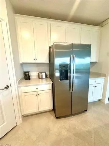 Kitchen featuring stainless steel fridge with ice dispenser, white cabinetry, and light tile patterned flooring