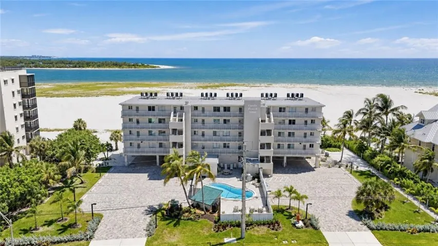 Beachfront condominium building with private balconies, an outdoor swimming pool, and dedicated parking - Virtually Edited Image
