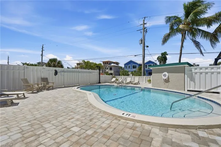 Outdoor pool with a paved deck, perimeter fencing, and an integrated spa - Virtually Edited Image