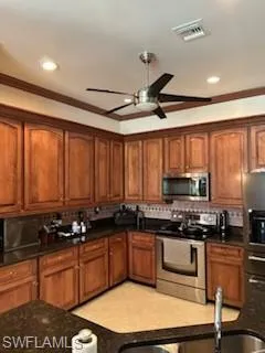 Kitchen with appliances with stainless steel finishes, backsplash, ceiling fan, and light tile floors