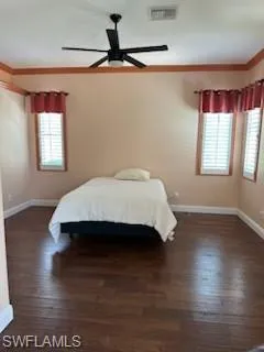 Unfurnished bedroom featuring crown molding, ceiling fan, dark hardwood / wood-style floors, and multiple windows