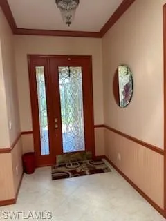 Carpeted foyer entrance with ornamental molding