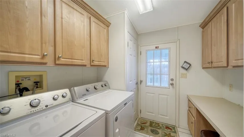 Laundry room has ample cabinets, desk & skylight