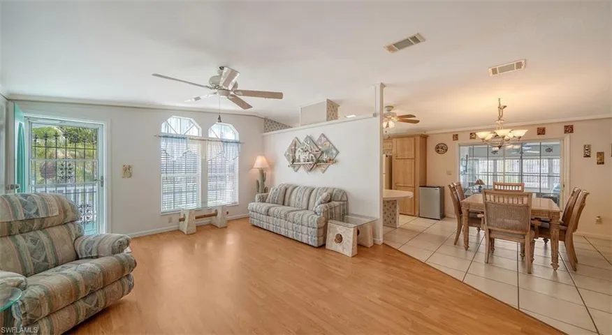 Living room featuring ceiling fan, light wood-type flooring, plenty of natural light, crown molding, and a chandelier