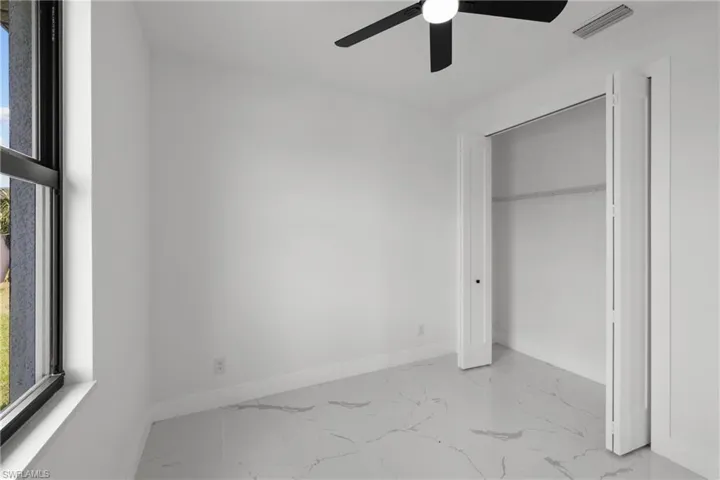 Unfurnished bedroom with baseboards, multiple windows, and marble finish floor