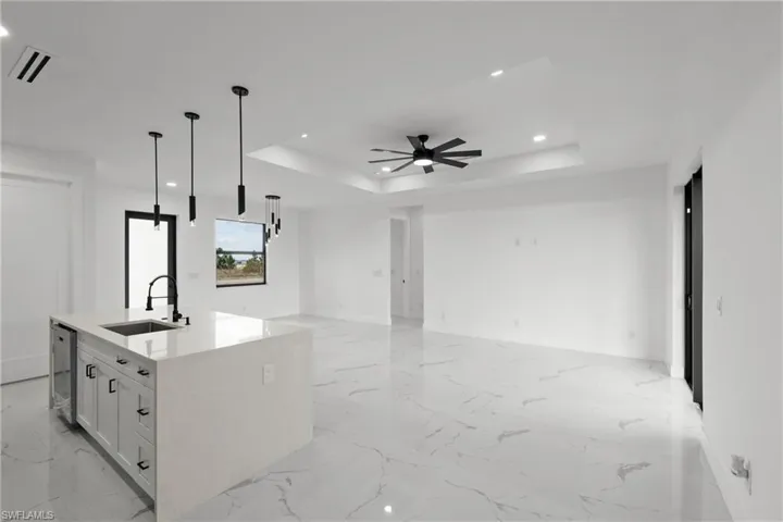 Kitchen featuring a sink, marble finish floor, a tray ceiling, and open floor plan