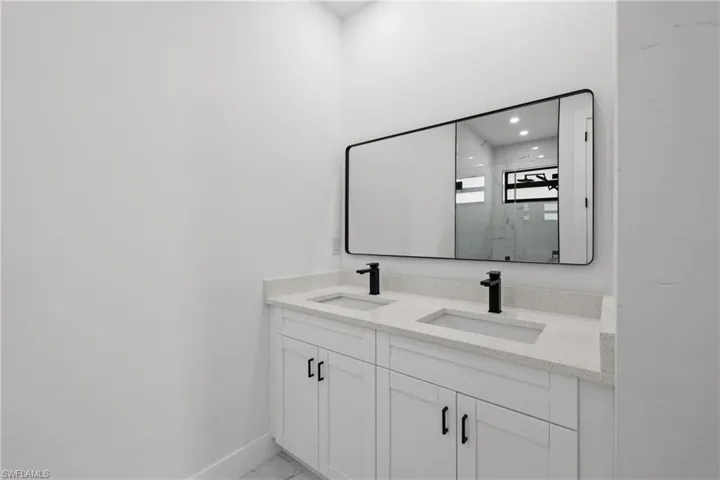 Full bathroom with baseboards, a sink, marble finish floor, and a marble finish shower