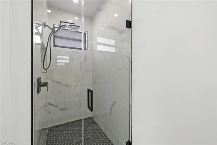 Bathroom with recessed lighting and a marble finish shower