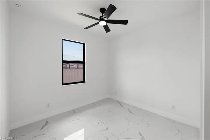 Empty room featuring a ceiling fan, baseboards, and marble finish floor