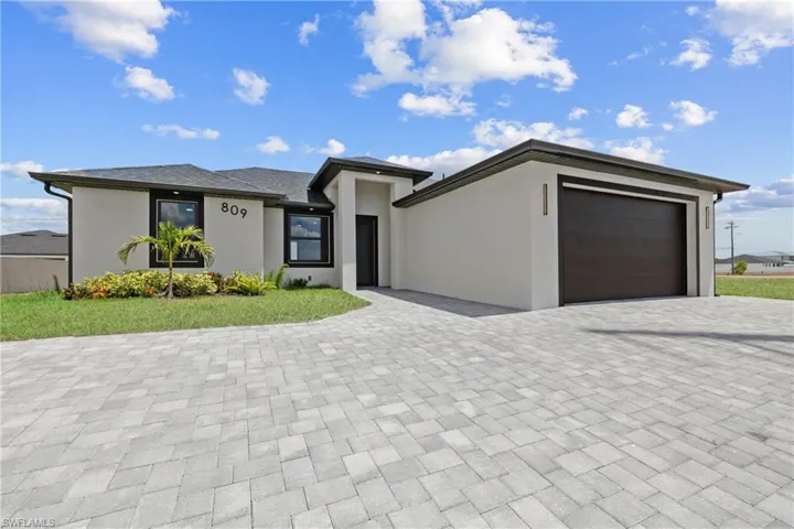 Prairie-style home featuring stucco siding, an attached garage, and decorative driveway