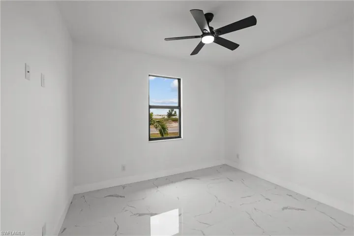 Empty room with baseboards, a ceiling fan, and marble finish floor